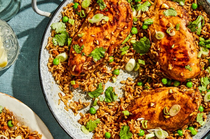 A Large Pan of Brown Rice Topped with Chicken Breasts and Spring Onions