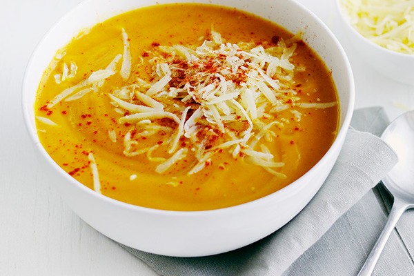 Bowl of sweet potato soup, topped with grated cheese