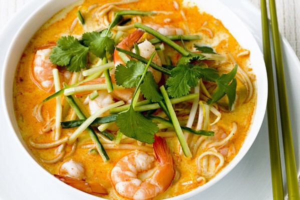 A bowl of prawn noodle soup topped with coriander garnish