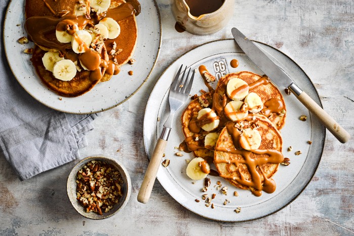 Biscoff Pancakes on two plates topped with sliced banana