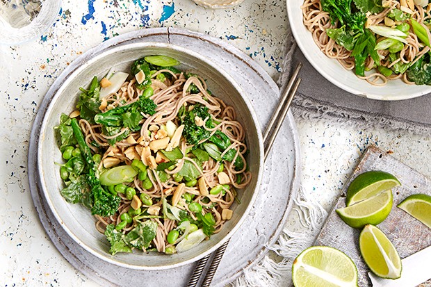 Broccoli and peanut soba noodles in a bowl with cut limes on the side