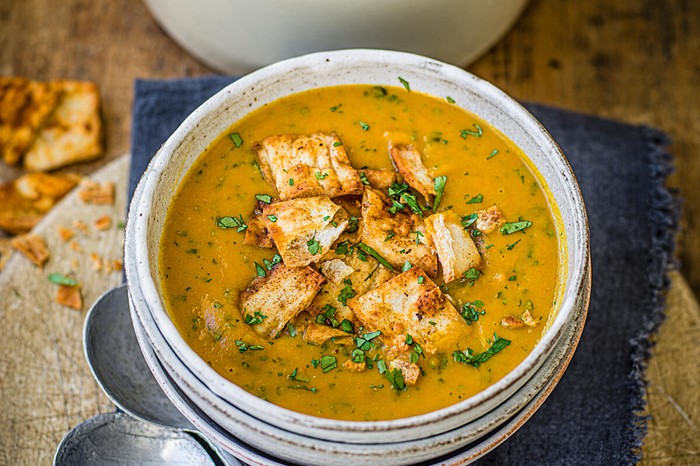 Carrot and coriander soup in a bowl with spicy flatbread croutons