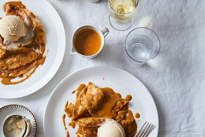 Two plates of pancakes topped with an espresso and salted caramel sauce and a scoop of ice cream