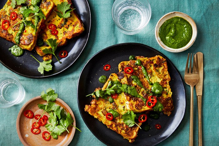 Two plates of masala French toast, topped with coriander chutney, chillies and coriander