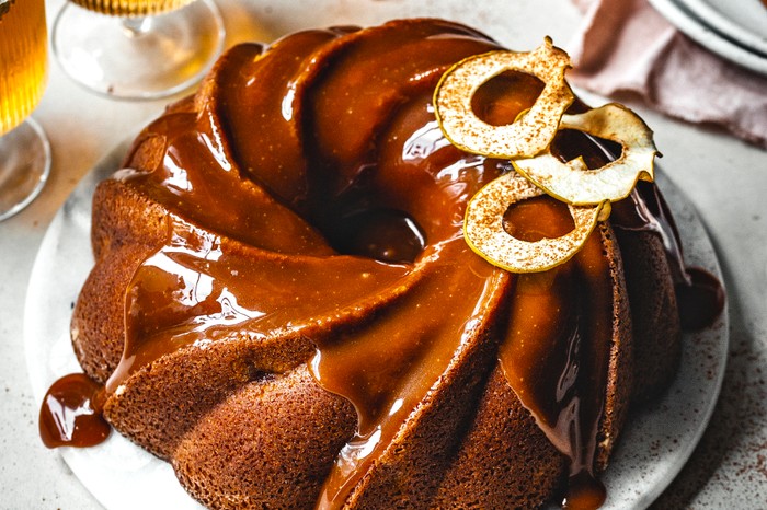A beautiful bundt cake topped with caramel sauce and golden apple slices