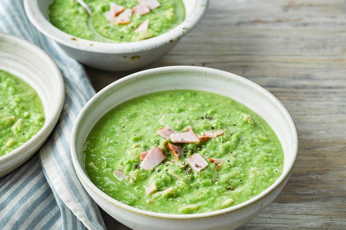 Three bowls of pea soup topped with ham slices