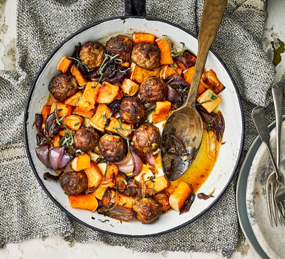 Meatball traybake with onion and butternut squash cubes, served in a large bowl with serving spoon