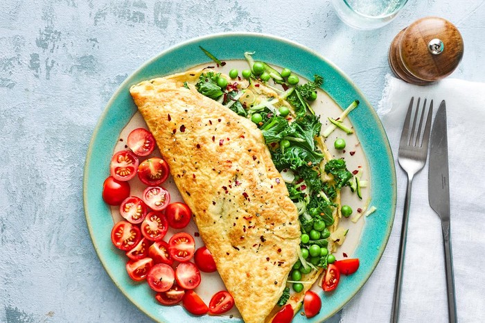Omelette Filled with Green Vegetables on a Plate with Tomatoes