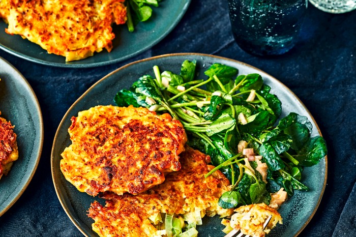 A blue plate topped with two golden fritters, green leaves and a fork