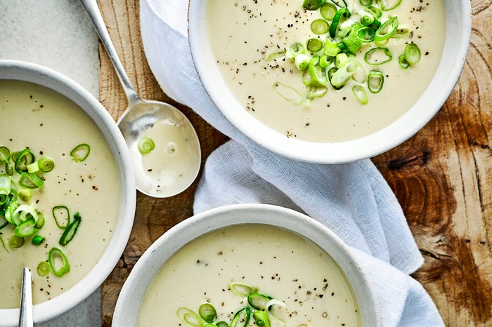 Three bowls of potato soup, topped with spring onions