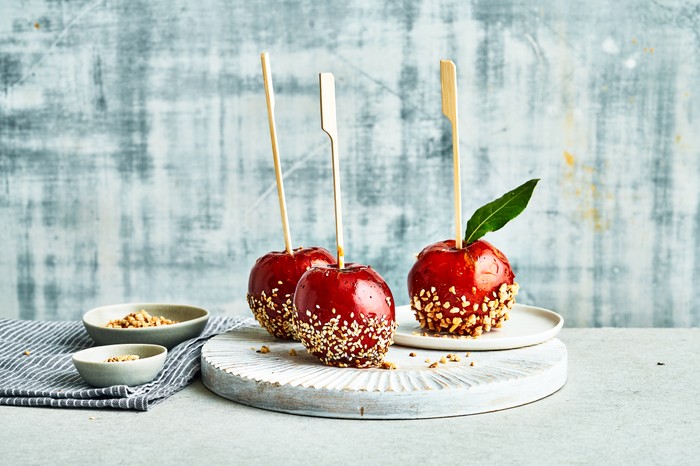 Three toffee apples against a white and grey backdrop