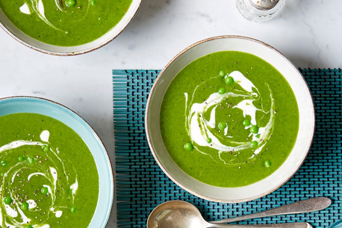 Three bowls of green spinach and pea soup, with a swirl of creme fraîche