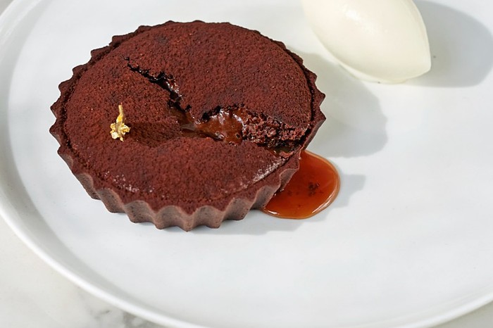 A chocolate tart on a white plate with a marble background
